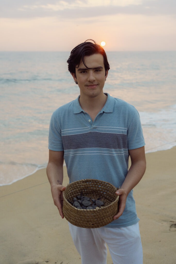 Alex Favero en una playa de la costa de Oaxaca, con una canasta tejida en las manos.