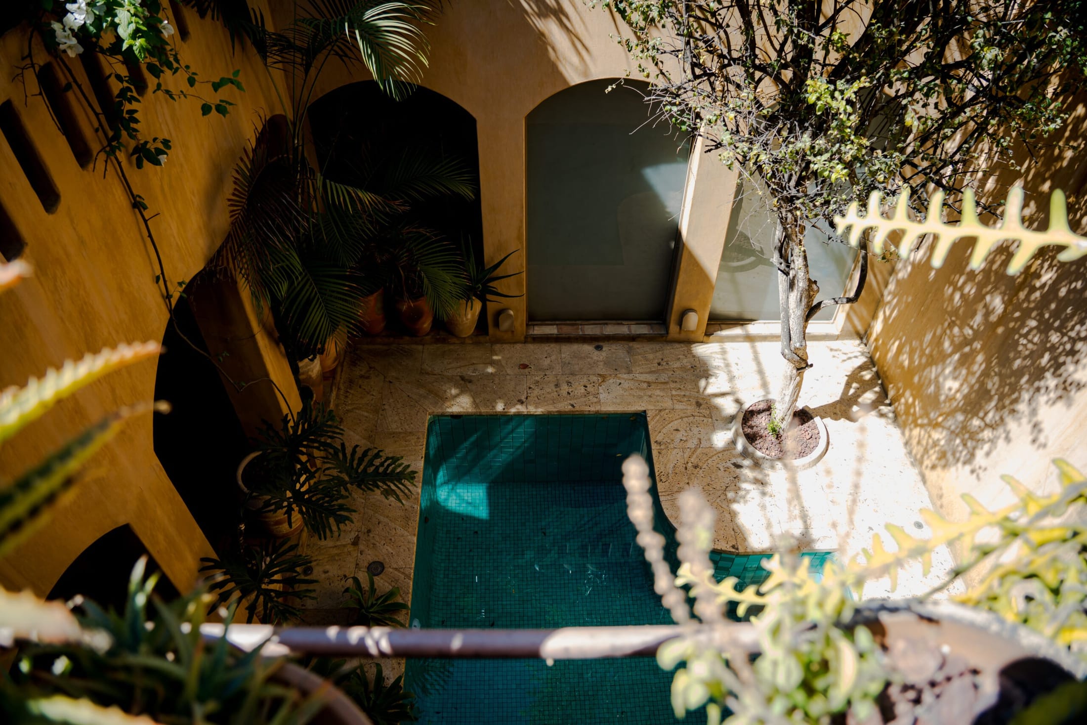 Vista aérea de una alberca geométrica integrada a un patio colonial restaurado, entre líneas minimalistas y arquitectura tradicional de cantera oaxaqueña.