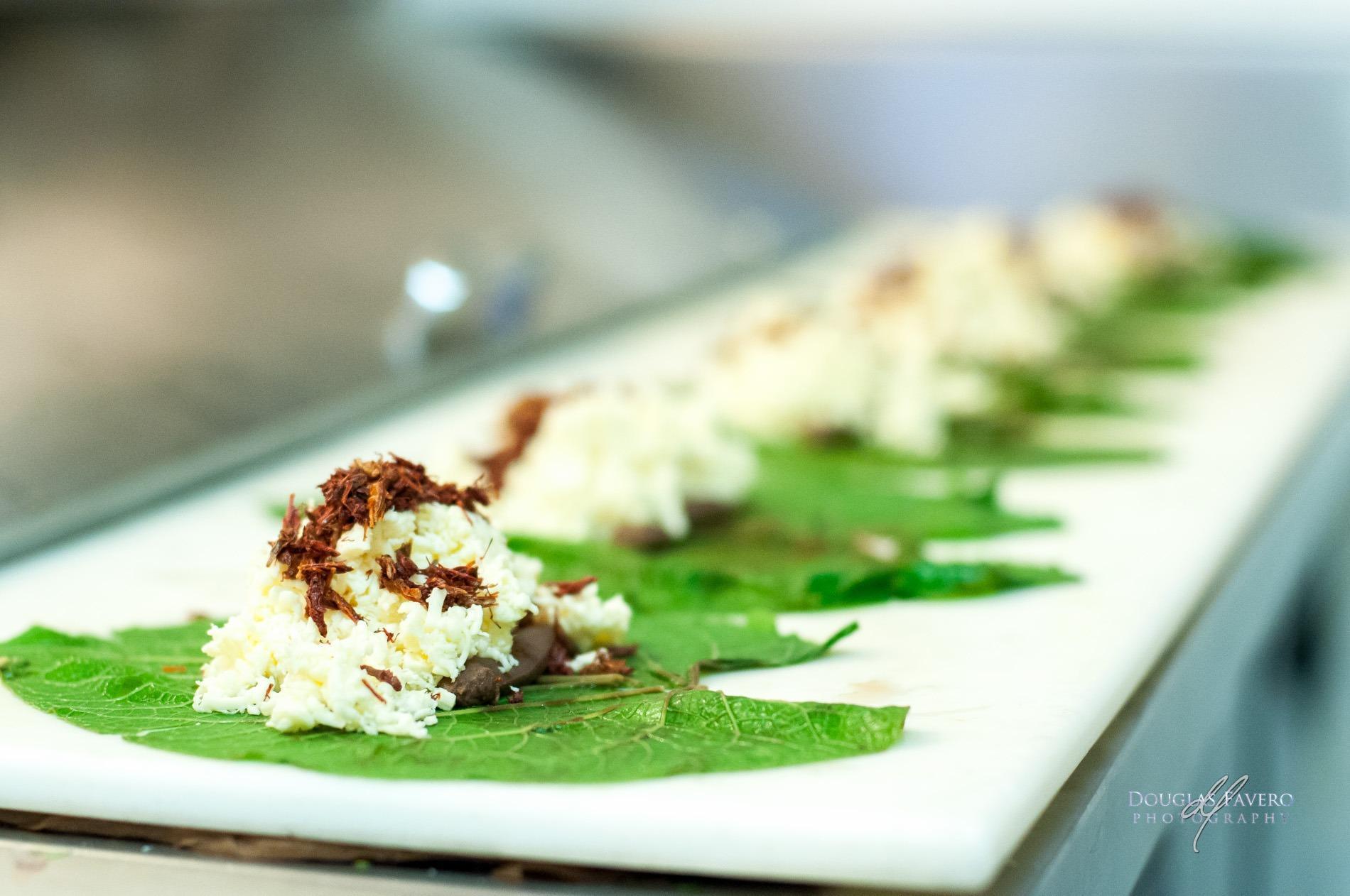 Quesillo deshebrado con chapulines encima, sobre hojas verdes y servido en una tabla blanca, en Oaxaca