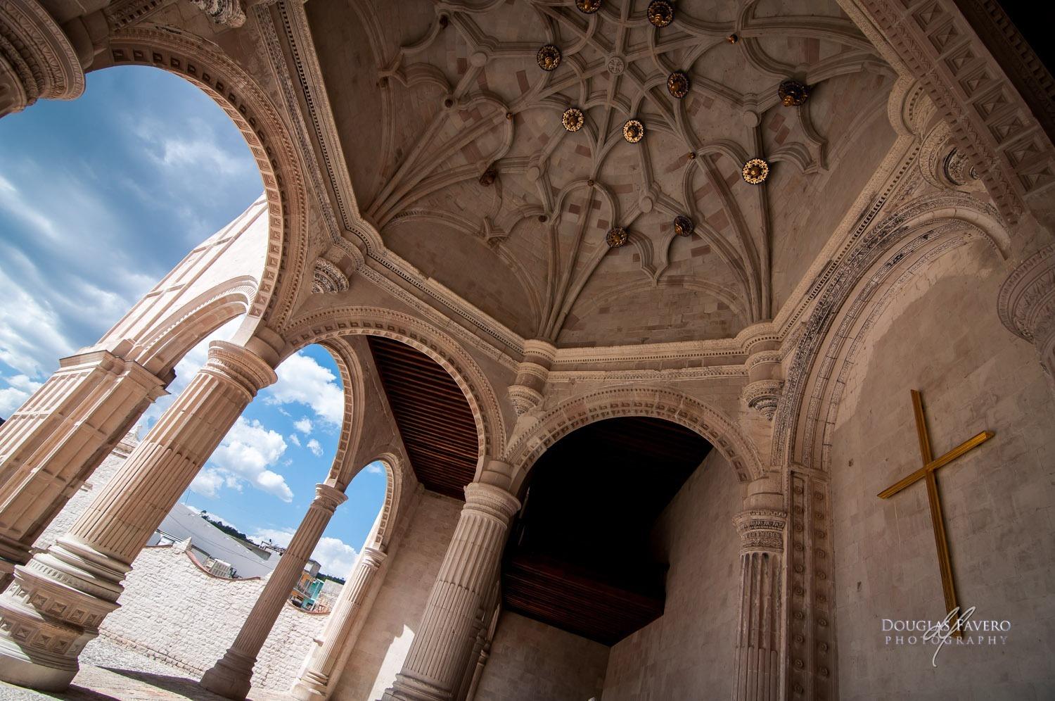 Arcos y columnas acanaladas de la capilla abierta de Teposcolula, con bóveda nervada y una cruz dorada